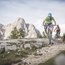 Zwei Mountainbiker fahren auf einem felsigen Bergpfad mit Bergen im Hintergrund