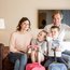 Family with two children sitting in living room with suitcases ready to travel